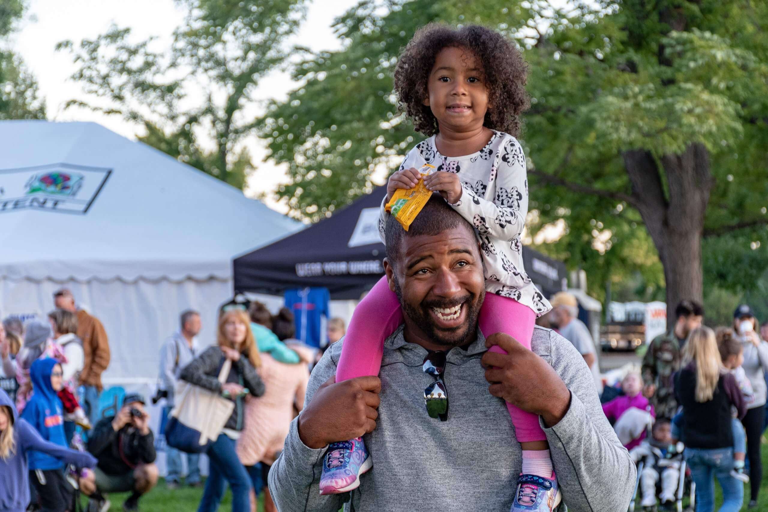 Father holding daughter on his shoulders.
